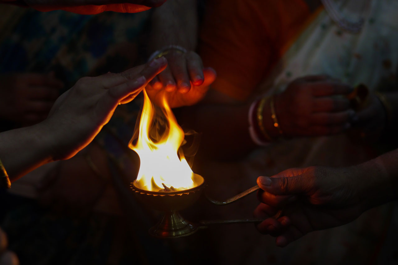 Hände am Licht einer traditionellen Arati-Zeremonie in Soma Bay